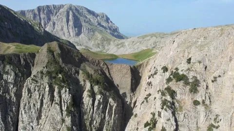 Remote Mountain Lake Surrounded by Cliffs and Rocks Stock Footage 303399239