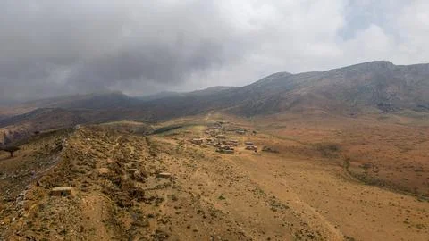 Remote mountain village under dramatic storm clouds Фото