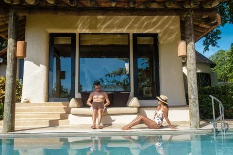 Remote online working digital nomad men and women and laptop sitting pool at a Stockfoto's