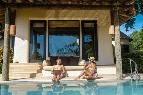 Remote online working digital nomad men and women and laptop sitting pool at a 스톡 사진