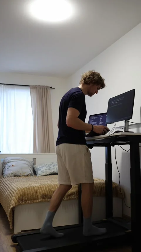 Remote programmer codes while walking on treadmill at standing desk Stock-Footage 346881377