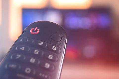 Remote smart TV control close-up on a background with television, selective f Stock Photos