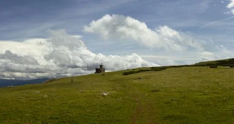 Remote Stone Mountain Chapel Standing on Vast Green Alpine Plateau Beneath .. Stock-Fotos