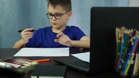 Remote study at home. a boy sitting at a table opens a marker to start writing Stock Footage 145145198