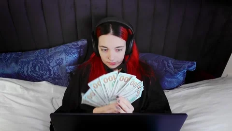 Remote support agent counting cash in bed wearing headset over laptop Stock Footage 343951146