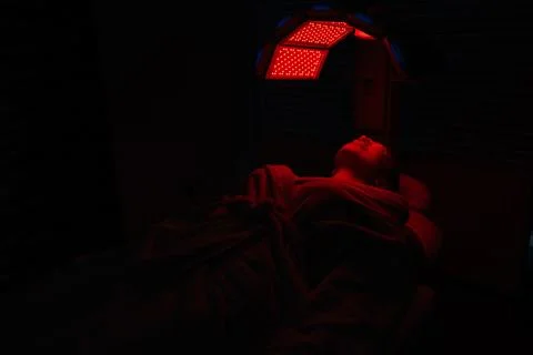 Remote view of female client in protective glasses having red LED light facial Stock Photos