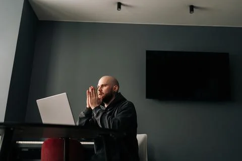 Remote view of focused male software developer with hands clasped, contemplating Foto stock
