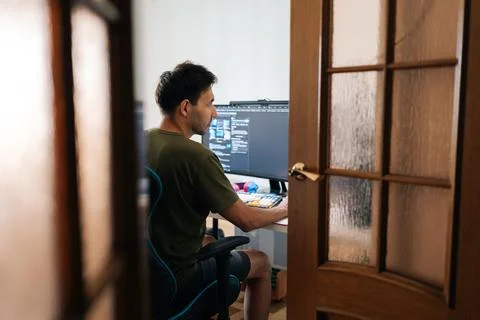 Remote view of focused programmer male working from home office using multiple Stock Photos