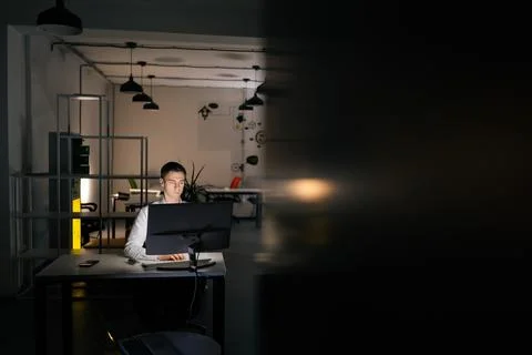 Remote view of focused young office worker male working at workplace on computer Stock Photos