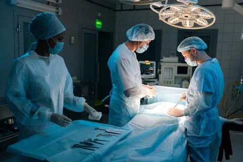 Remote view of skilled diverse surgeons and nurse wearing sterile gloves Stock Photos