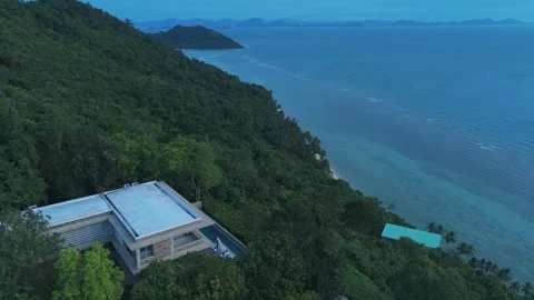 Remote villa above ocean cliffs. Modern villa nestled on lush hillside offers Stock Footage 312743993