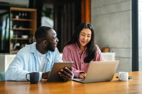 Remote work and digital business. Diverse couple collaborating online, managing Stock Photos