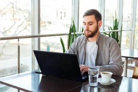 Remote work. Businessman using laptop, caucasian man sitting at table in cafe Stock Photos
