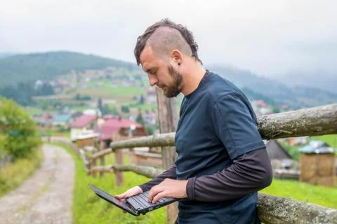 Remote work concept: a man working on a laptop outdoors. Stock Photos