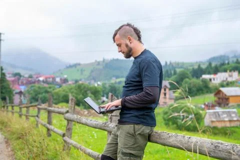 Remote work concept: a man working on a laptop outdoors. Stock Photos