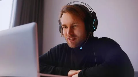 Remote work concept. Young man with headphones having online meeting on his Stock Photos