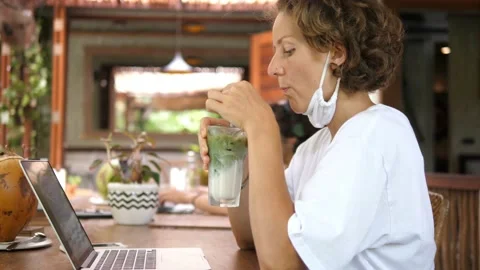 Remote work during a covid-19 pandemic. A young woman in a face mask working at Stock Footage 154384070