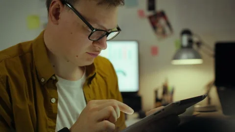 Remote work. An experienced specialist peers intently into a tablet display, Stock Footage 281108088
