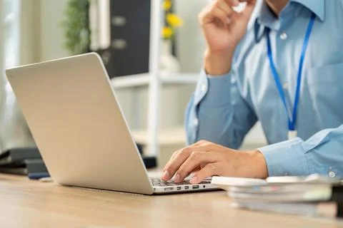 Remote Work Focus. Professional man typing on laptop in modern office. Stock Photos