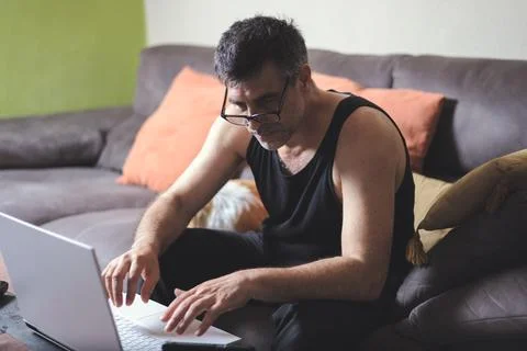 Remote Work: Focused man with dark hair with Laptop in the Comfort of Home Foto stock