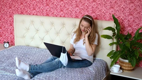 Remote work from home. Beautiful Caucasian girl writes notes in laptop in mask Stock Footage 128733678