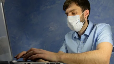 Remote work at home. Masked office worker, a man sits at home and works Stock Footage 128702625