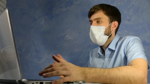 Remote work at home. Masked office worker, a man sits talking on a video link Stock Footage 128702636