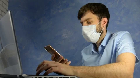 Remote work at home. Masked worker, a man sits at home typing on the phone 스톡 동영상 128702628