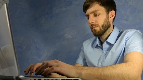 Remote work at home. Office worker, a man in a blue shirt sits at home and works Stock Footage 128702655