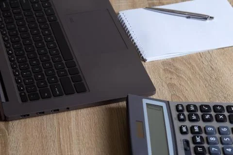 Remote work laptop calculator notepad with pen on the table Stock Photos