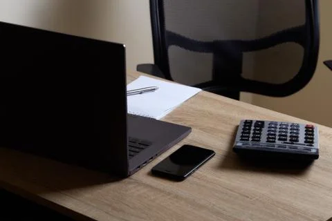 Remote work laptop calculator notepad with pen and phone on the table near ch Stock Photos