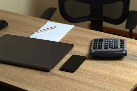 Remote work laptop calculator notepad with pen and phone on the table near ch Stock Photos