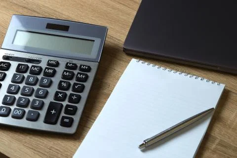 Remote work laptop calculator notepad with pen on the table Stock Photos