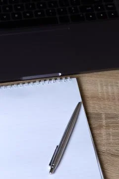 Remote work laptop notepad with pen on the table Stock Photos