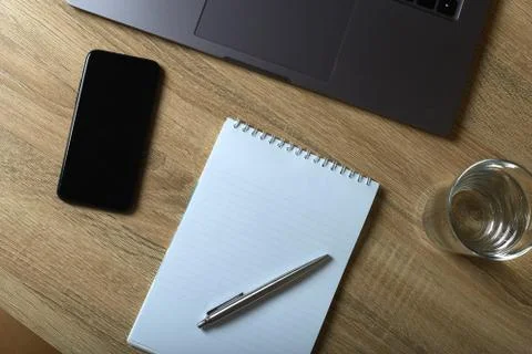 Remote work laptop notepad with pen and glass of water on the table Stock-Fotos