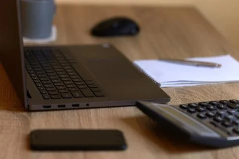 Remote work laptop phone notepad calculator mug on the table Stock Photos