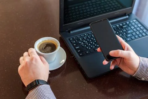 Remote work. Man using laptop, holding smart phone for business work or study Stock Photos