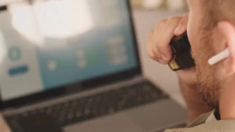 Remote Work Mode: Man on Voice Call with Laptop While Vaping Stock Footage 321985315