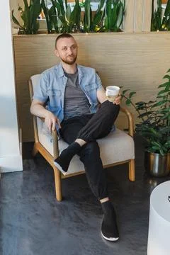 Remote work from a modern space with plants and a coffee cup in hand while .. Stock Photos