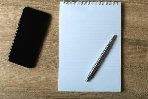 Remote work phone notepad with pen on the table Stock Photos