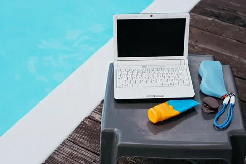 Remote Work by the Pool with Laptop and Sunscreen Stock Photos