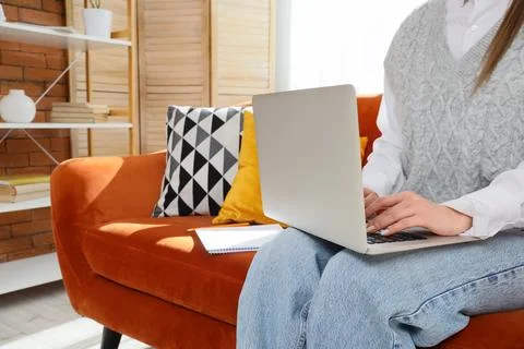 Remote work productivity: woman using laptop on sofa for online business and  Stock Photos