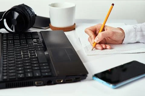Remote work. Woman makes notes in notebook and using laptop for study. Distan 스톡 사진
