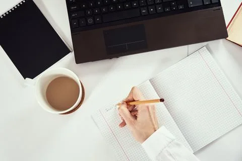 Remote work. Woman makes notes in notebook and using laptop for study. Distan 스톡 사진