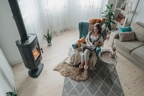 Remote work. Young woman using laptop in a cozy armchair and plaid sitting by 스톡 사진