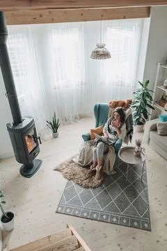Remote work. Young woman using laptop in a cozy armchair and plaid sitting by Stock Photos