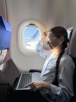 Remote worker on airplane window seat preparing laptop workflow before take.. Stock Photos