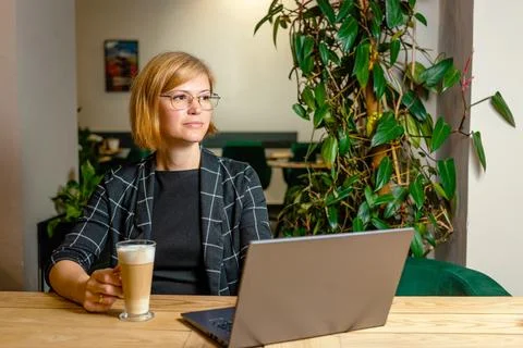 Remote Worker Drinking Coffee Beside Her Laptop Stock Photos