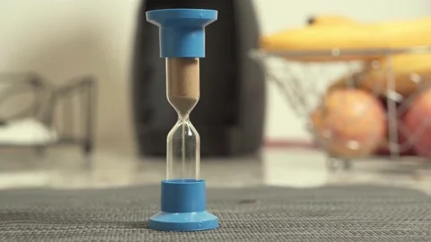 Remote worker drinking coffee with hourglass on foreground. Video stock 145992186