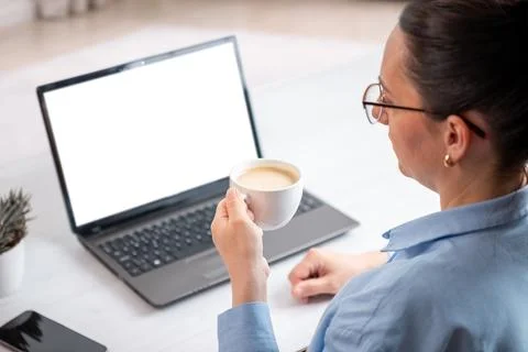 Remote worker holding coffee cup near isolated laptop display in minimalist.. Stock-Fotos